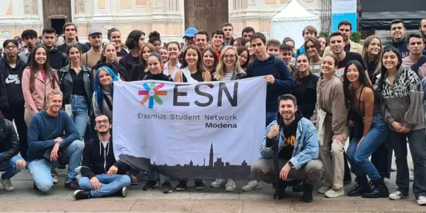 International students posing with the Flag of ESN Modena