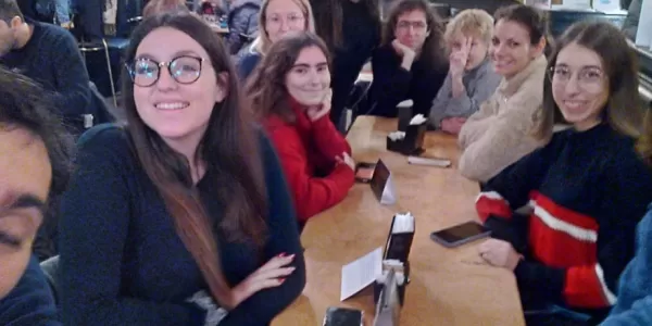 A group of people sitting at the café table is looking at the camera and smiling.