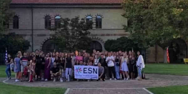 group picture in the middle of the university courtyard. in the middle there is the esnAncona flag.