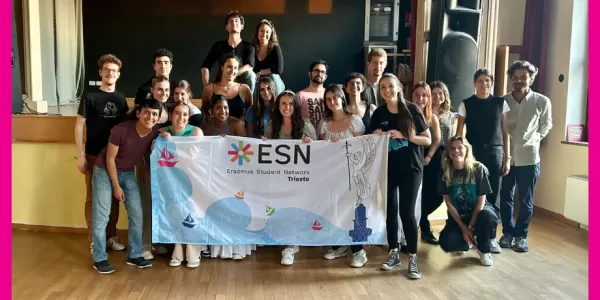The picture shows the participants close together in a group in the theatre where the event took place, holding ESN Trieste's flag and smiling at the camera.
