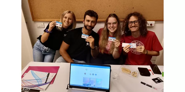 The event manager, the treasurer, the president and a staff member are in a the ESN Ravenna's stand and posing for a picture with their ESNCard
