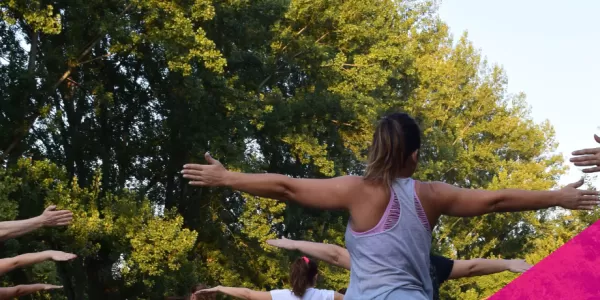 People doing Yoga in a park and the name of the event.