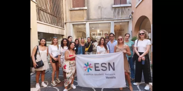 Group picture with the ESN Venezia flag standing near a fountain with a statue