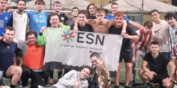 Group of international students with ESN Modena flag on a futsal pitch
