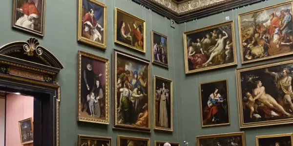 The image displays a wall from a museum salon full of paintings