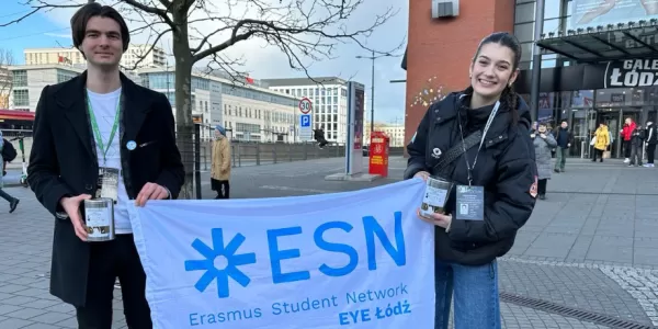 The image shows two participants of the event standing with the ESN-EYE flag in fron of a popular mall in Lodz.