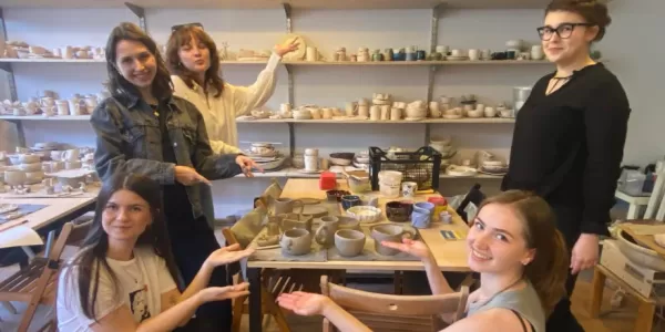 The image shows participants of the activity in a pottery workshop.