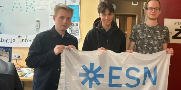 The image shows participants of the event holding the ESN-EYE flag inside the Radio Żak station.