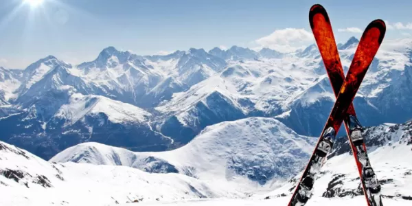 Image of a red pair of ski in the snow in front of mountains