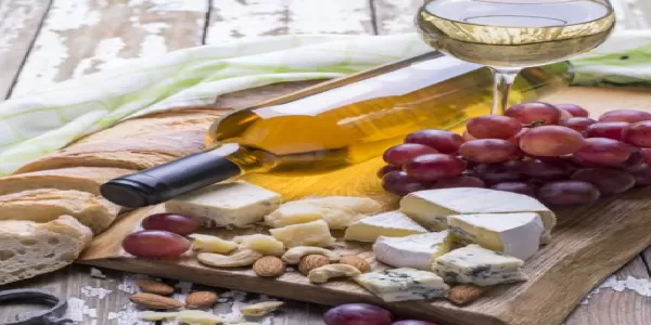 Image of a glass of wine and multiple types of cheese