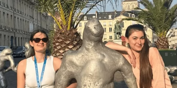 Two staff members leaning on a statue in the center of Caen