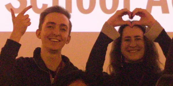 2 participants and 2 coordinators in front of a screen with the welcome presentation; all look happy