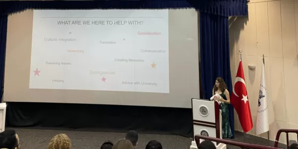 President of ESN Dokuz Eylul standing by a podium doing a presentation about Erasmus