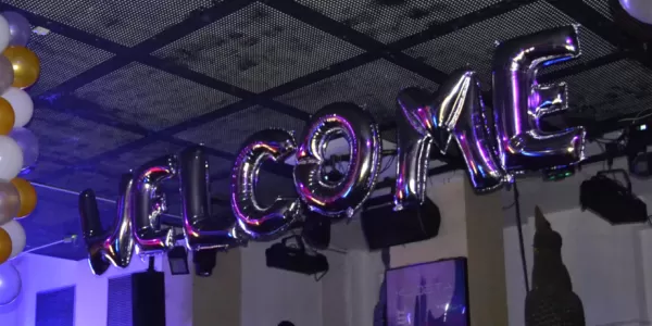 People enjoyin the party and the world "Welcome" done with balloons