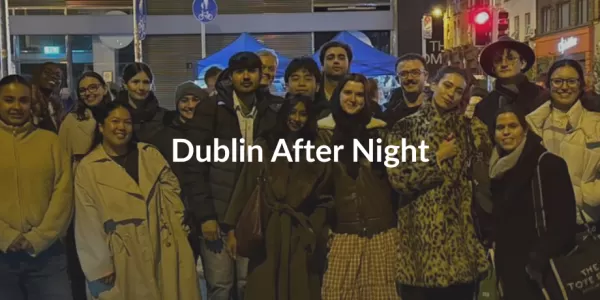 A group of people smiling at night in Dublin, dressed warmly. Bright streetlights and a red traffic light are visible. Text reads "Dublin After Night." ESN logo in the corner.