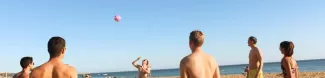 international students playing volleybal on the beach