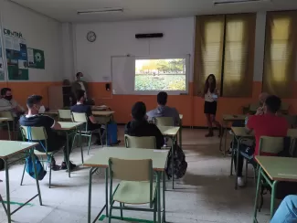 An Erasmus student is doing a presentation on her country to a classroom full of students.