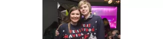 Two students wearing Christmas Sweatshirts, posing next to each other. 