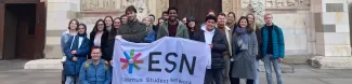 International students posing with the Flag of ESN Modena in front of the Cathedral of the city of Modena