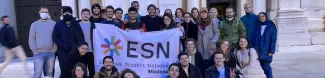 International students posing with the Flag of ESN Modena in front of the Cathedral of the city of Reggio Emilia