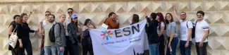 group of international students posing with the ESN Modena flag in front of Diamanti Palace in Ferrara