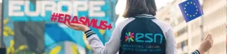 A girl holding a sign that says "Erasmus+"