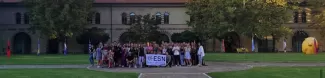 group picture in the middle of the university courtyard. in the middle there is the esnAncona flag.