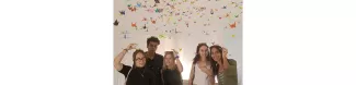 Group photo taken inside the origami lab surrounded by many hanging cranes