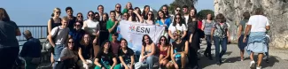 Erasmus students and volunteers in the Strada Napoleonica holding ESN Trieste's flag