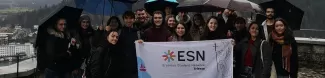 Group of Erasmus students and volunteers in Bled holding ESN Trieste's flag