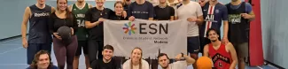 Group of international students with ESN Modena flag on a basketball pitch