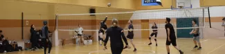 Students playing volleyball with a large audience