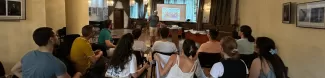 a dozen of people sitting watching to a boy presenting