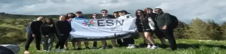 A group of people on a mountain with an ESN flag